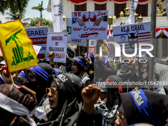 Muslims hold up posters during a pro-Palestinian rally on the eve of the one-year anniversary of the Israel-Hamas conflict in Surabaya, Indo...