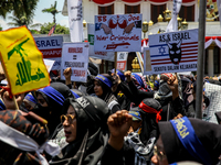 Muslims hold up posters during a pro-Palestinian rally on the eve of the one-year anniversary of the Israel-Hamas conflict in Surabaya, Indo...