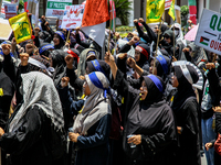 Muslims hold up posters during a pro-Palestinian rally on the eve of the one-year anniversary of the Israel-Hamas conflict in Surabaya, Indo...