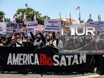 Muslims hold up posters during a pro-Palestinian rally on the eve of the one-year anniversary of the Israel-Hamas conflict in Surabaya, Indo...