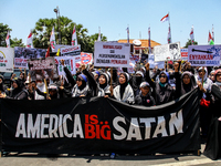 Muslims hold up posters during a pro-Palestinian rally on the eve of the one-year anniversary of the Israel-Hamas conflict in Surabaya, Indo...