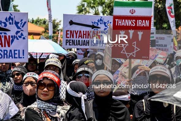 Muslims hold up posters during a pro-Palestinian rally on the eve of the one-year anniversary of the Israel-Hamas conflict in Surabaya, Indo...