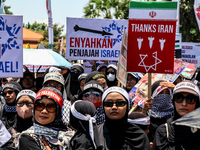 Muslims hold up posters during a pro-Palestinian rally on the eve of the one-year anniversary of the Israel-Hamas conflict in Surabaya, Indo...