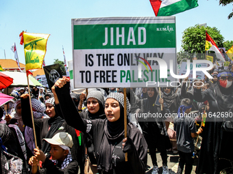 Muslims hold up posters during a pro-Palestinian rally on the eve of the one-year anniversary of the Israel-Hamas conflict in Surabaya, Indo...