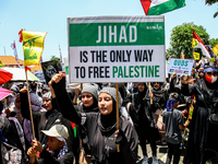 Muslims hold up posters during a pro-Palestinian rally on the eve of the one-year anniversary of the Israel-Hamas conflict in Surabaya, Indo...