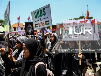 Muslims hold up posters during a pro-Palestinian rally on the eve of the one-year anniversary of the Israel-Hamas conflict in Surabaya, Indo...