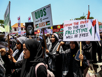 Muslims hold up posters during a pro-Palestinian rally on the eve of the one-year anniversary of the Israel-Hamas conflict in Surabaya, Indo...