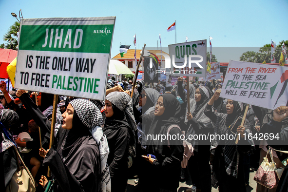 Muslims hold up posters during a pro-Palestinian rally on the eve of the one-year anniversary of the Israel-Hamas conflict in Surabaya, Indo...