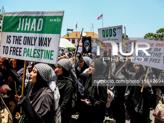 Muslims hold up posters during a pro-Palestinian rally on the eve of the one-year anniversary of the Israel-Hamas conflict in Surabaya, Indo...