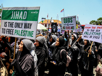 Muslims hold up posters during a pro-Palestinian rally on the eve of the one-year anniversary of the Israel-Hamas conflict in Surabaya, Indo...