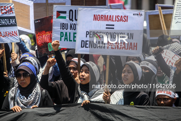 Muslims hold up posters during a pro-Palestinian rally on the eve of the one-year anniversary of the Israel-Hamas conflict in Surabaya, Indo...