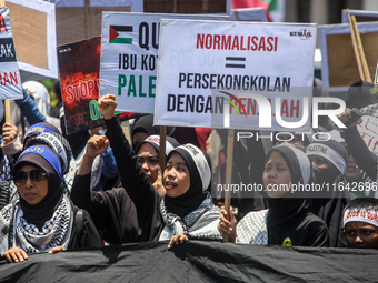 Muslims hold up posters during a pro-Palestinian rally on the eve of the one-year anniversary of the Israel-Hamas conflict in Surabaya, Indo...