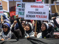 Muslims hold up posters during a pro-Palestinian rally on the eve of the one-year anniversary of the Israel-Hamas conflict in Surabaya, Indo...