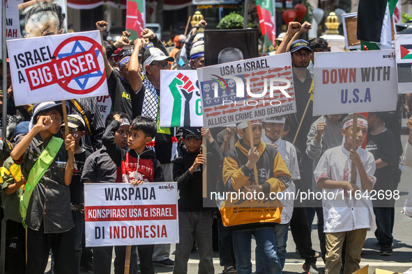 Muslims hold up posters during a pro-Palestinian rally on the eve of the one-year anniversary of the Israel-Hamas conflict in Surabaya, Indo...