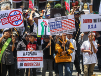 Muslims hold up posters during a pro-Palestinian rally on the eve of the one-year anniversary of the Israel-Hamas conflict in Surabaya, Indo...