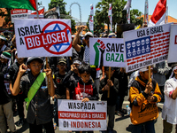 Muslims hold up posters during a pro-Palestinian rally on the eve of the one-year anniversary of the Israel-Hamas conflict in Surabaya, Indo...