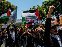 Muslims hold up posters during a pro-Palestinian rally on the eve of the one-year anniversary of the Israel-Hamas conflict in Surabaya, Indo...