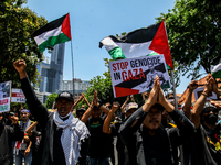 Muslims hold up posters during a pro-Palestinian rally on the eve of the one-year anniversary of the Israel-Hamas conflict in Surabaya, Indo...