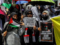 Muslims hold up posters during a pro-Palestinian rally on the eve of the one-year anniversary of the Israel-Hamas conflict in Surabaya, Indo...