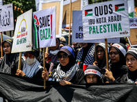 Muslims hold up posters during a pro-Palestinian rally on the eve of the one-year anniversary of the Israel-Hamas conflict in Surabaya, Indo...