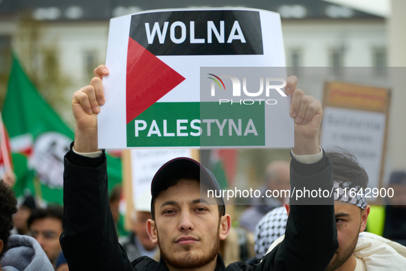 A man holds a sign reading ''Free Palestine'' in Warsaw, Poland on 05 October, 2024. About a hundred people marched from the Royal Castle Sq...