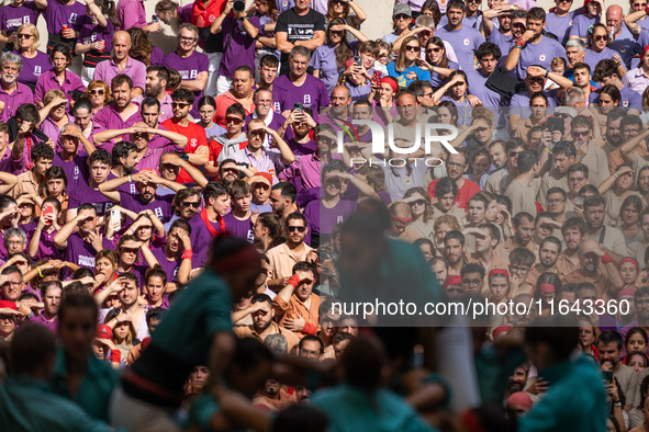 People watch members of the colla Castellers de Vilafranca build a human tower during the Concurs de Castells competition in Tarragona, Spai...