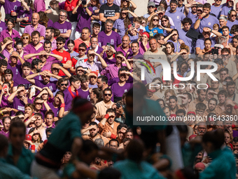 People watch members of the colla Castellers de Vilafranca build a human tower during the Concurs de Castells competition in Tarragona, Spai...