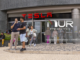 In Lisbon, Portugal, on October 6, 2024, people walk by a Tesla dealer. Tesla's third-quarter 2024 results show strong vehicle production, w...