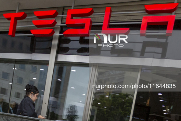 A person is seen near a Tesla dealer in Lisbon, Portugal, on October 6, 2024. Tesla's third-quarter 2024 results show strong vehicle product...