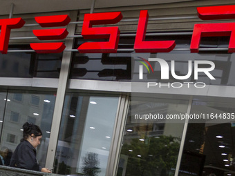 A person is seen near a Tesla dealer in Lisbon, Portugal, on October 6, 2024. Tesla's third-quarter 2024 results show strong vehicle product...