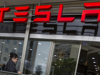 A person is seen near a Tesla dealer in Lisbon, Portugal, on October 6, 2024. Tesla's third-quarter 2024 results show strong vehicle product...