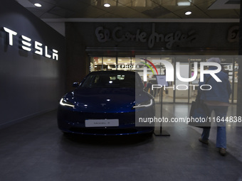 A person walks by a Tesla Model 3 car in Lisbon, Portugal, on October 6, 2024. Tesla's third-quarter 2024 results show strong vehicle produc...