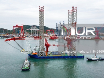 A high-horsepower tugboat pulls the fourth-generation offshore wind power construction platform ''Ganghangping 5'' off the Haixi Heavy Machi...