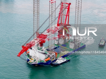 A high-horsepower tugboat pulls the fourth-generation offshore wind power construction platform ''Ganghangping 5'' off the Haixi Heavy Machi...