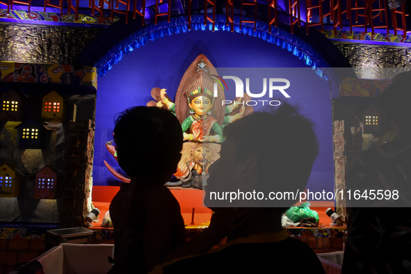 A man stands with his child in front of an idol of Goddess Durga at a temporary place of worship or Pandal in Habra, India, on October 6, 20...