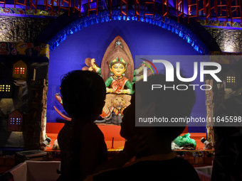 A man stands with his child in front of an idol of Goddess Durga at a temporary place of worship or Pandal in Habra, India, on October 6, 20...