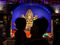 A man stands with his child in front of an idol of Goddess Durga at a temporary place of worship or Pandal in Habra, India, on October 6, 20...