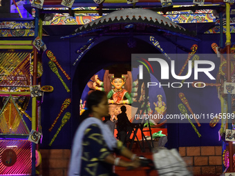 A lady rides past a Pandal on her bicycle during the Durga Puja festival in Kolkata, India, on October 6, 2024. (