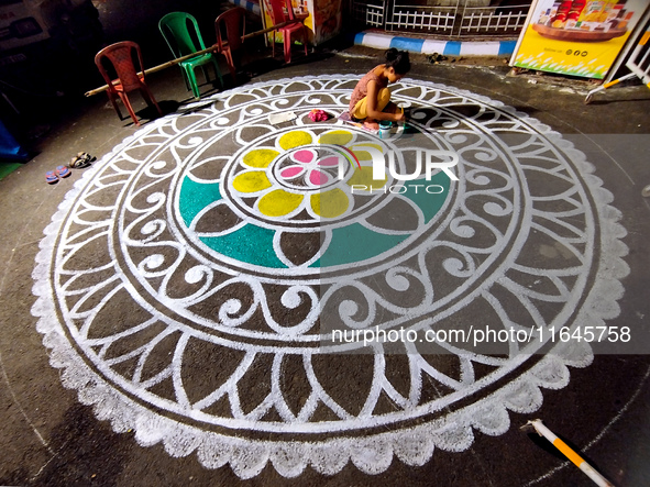 A woman creates alpona outside a Pandal during the Durga Puja festival in Kolkata, India, on October 6, 2024. 