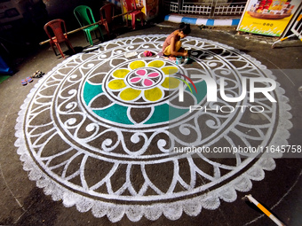 A woman creates alpona outside a Pandal during the Durga Puja festival in Kolkata, India, on October 6, 2024. (