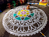 A woman creates alpona outside a Pandal during the Durga Puja festival in Kolkata, India, on October 6, 2024. (