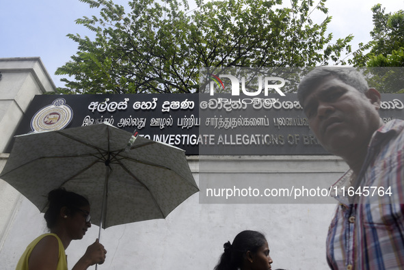 People walk in front of the Commission to Investigate Allegations of Bribery or Corruption office in Colombo, Sri Lanka, on October 4, 2024....