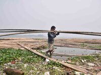 An Indian laborer carries bamboo at a bamboo market on the banks of the Brahmaputra River in Guwahati, India, on April 6, 2018. The Brahmapu...