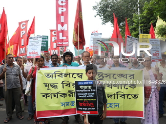 A holds a poster while the Communist Party of India (Marxist), West Bengal, holds posters during a protest amid the ongoing conflict in Gaza...