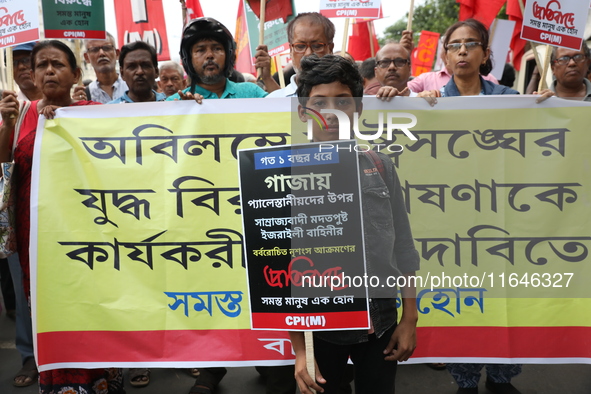 A boy holds a poster while the Communist Party of India (Marxist), West Bengal, holds posters and shouts slogans during a protest march amid...