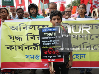 A boy holds a poster while the Communist Party of India (Marxist), West Bengal, holds posters and shouts slogans during a protest march amid...