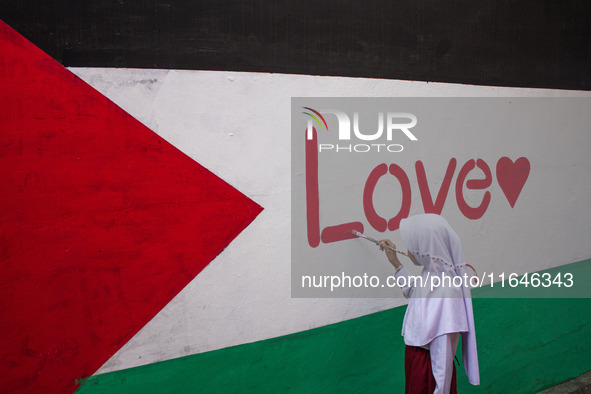 Students paint a mural to support the Palestinian people on a wall in the Liogenteng settlement area in Bandung, West Java, Indonesia, on Oc...