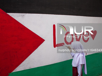 Students paint a mural to support the Palestinian people on a wall in the Liogenteng settlement area in Bandung, West Java, Indonesia, on Oc...