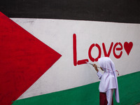 Students paint a mural to support the Palestinian people on a wall in the Liogenteng settlement area in Bandung, West Java, Indonesia, on Oc...