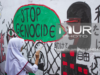 Students paint a mural to support the Palestinian people on a wall in the Liogenteng settlement area in Bandung, West Java, Indonesia, on Oc...